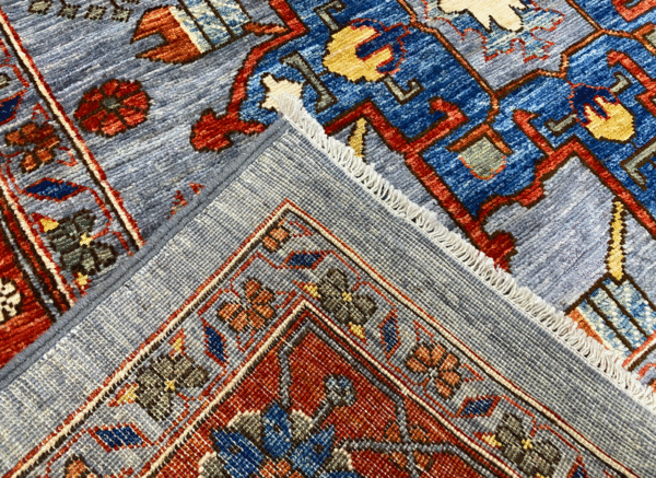 This bold tribal area rug is 9x12 featuring large tribal geometric shapes with bold red, blue and multicolored tones. This rug is hand knotted with wool.