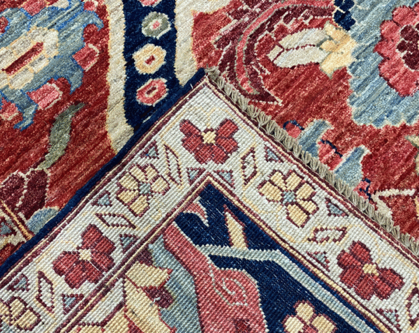 This bold tribal area rug is 9x12 featuring large tribal geometric shapes with bold red, blue and multicolored tones. This rug is hand knotted with wool.