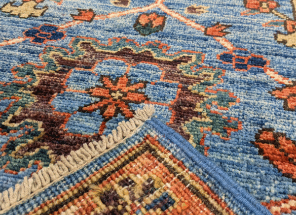 Long 3x10 area rug runner with a blue background and orange and yellows geometric designs. This rug features a border and short fringe.