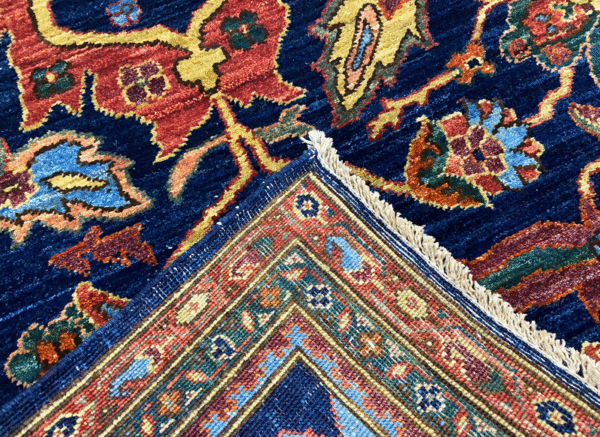 Stunning 6x9 rug with deep blues, orange, and yellows. This rug features a geometric pattern with a border and short fringe.