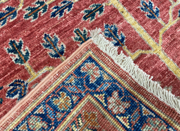 Aryana 3x10 area rug with a red background and tribal yellow and blue designs. This rug is hand-knotted with wool.