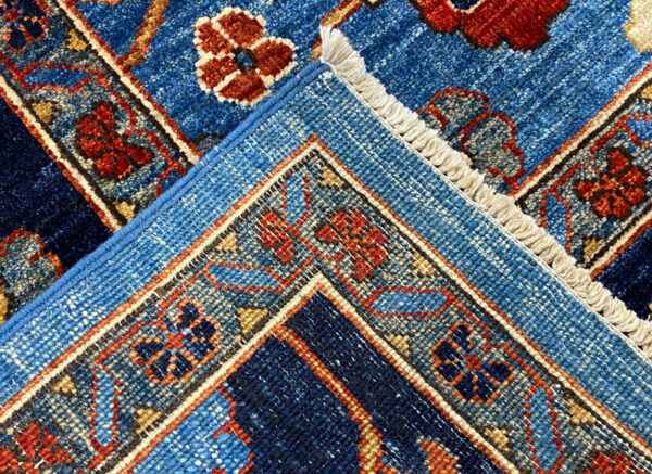 This bold tribal area rug is 8x10 featuring large tribal geometric shapes with bold ocean blue and multicolored tones. This rug is hand knotted with wool.