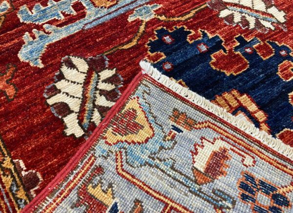 Stunning long 3x10 area rug runner with a deep red background. This rug features a geometric pattern with blue and yellow tones and a border and short fringe.
