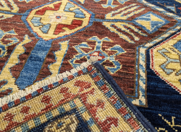 Stunning long 3x10 area rug runner with a deep blue background, yellow, and red. This rug features a geometric pattern with a border and short fringe.