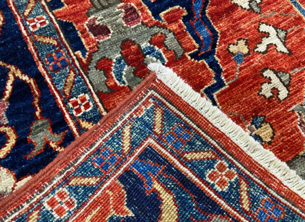 Bold large rug with deep rust tones and a blue border. This area rug is hand-knotted with wool.