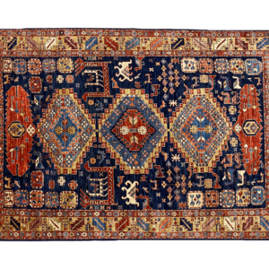 Bold area rug with tribal shapes in red, rust and gold. The background is navy with a gold border. This hand-knotted wool rug.