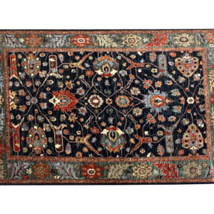 Large 6 x 9 area rug with a navy background and multicolored tribal designs. This rug is hand-knotted with wool.