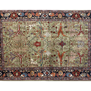 Large 8 x 10 Tribal Aryana area rug with a green background and blue and rust border with short fringe.