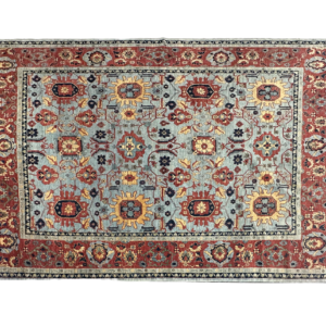 Traditional and tribal styled area rug with blue and red tones. This rug is hand-knotted with wool.