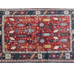 Tribal 6' x 9' area rug featuring a bold red field and navy border. This rug is hand-knotted with wool.