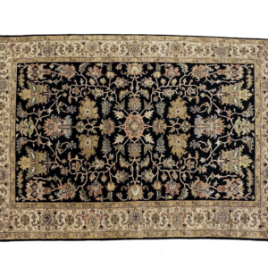 Traditional styled 6x9 area rug with a dark background and a gold border. This rug is hand-knotted with wool and features short fringe.