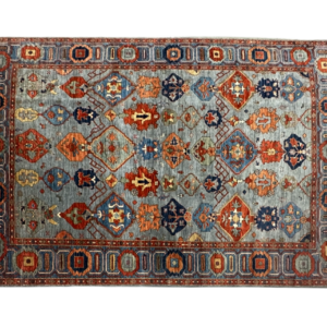 Bold 6x9 area rug with a blue background and geometrical designs. This rug is hand-knotted with wool.